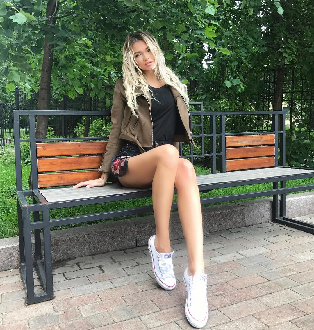 Блондинка раздвигает ноги на скамейке в парке